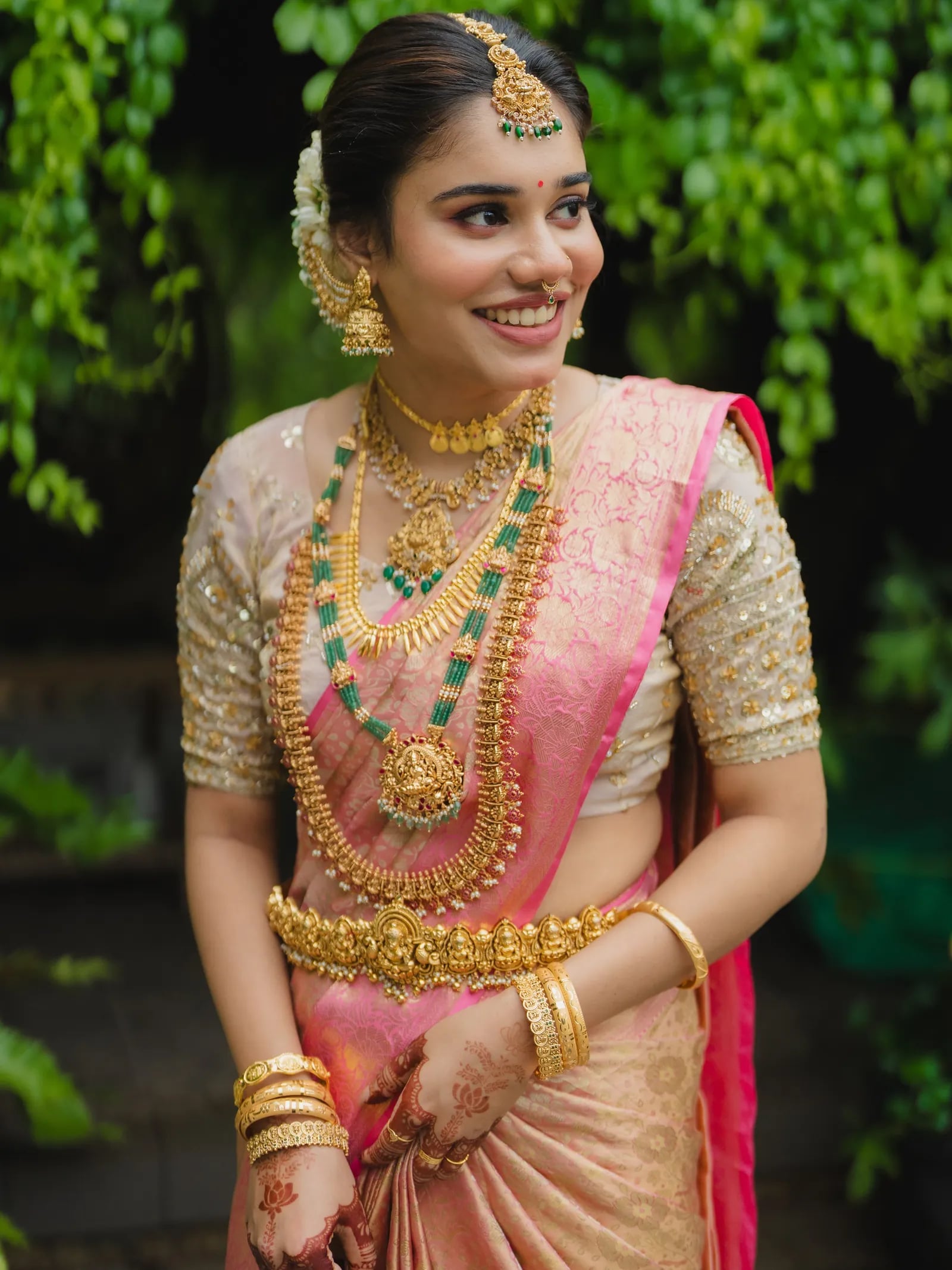 Bride in a pink and gold sari with traditional wedding jewellery